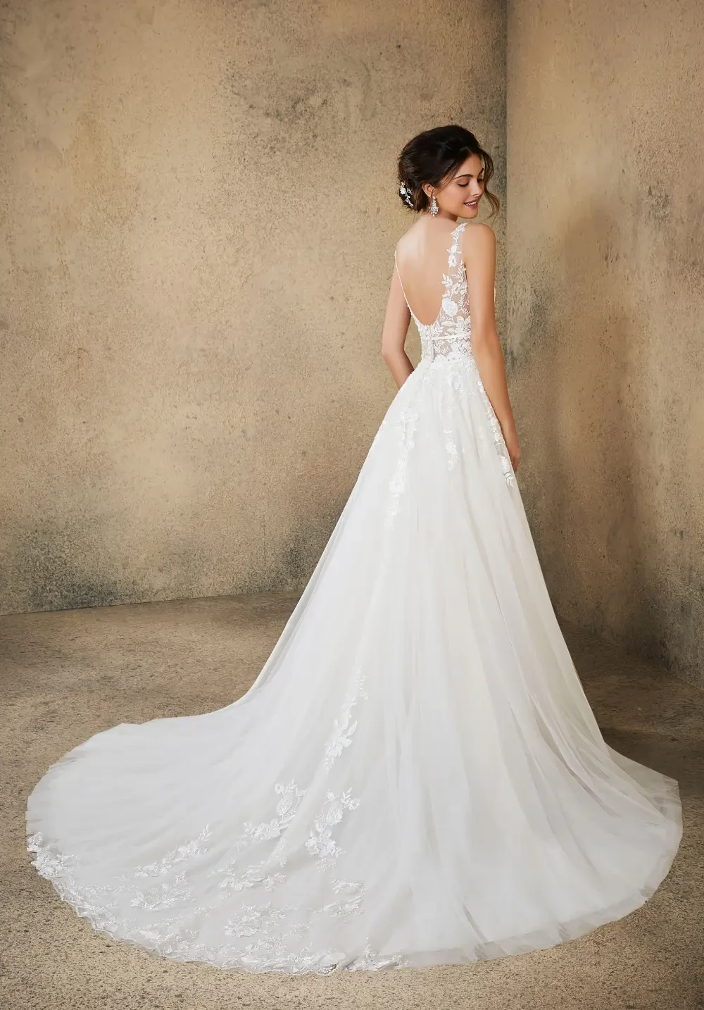 model is wearing a sleeveless open back wedding dress