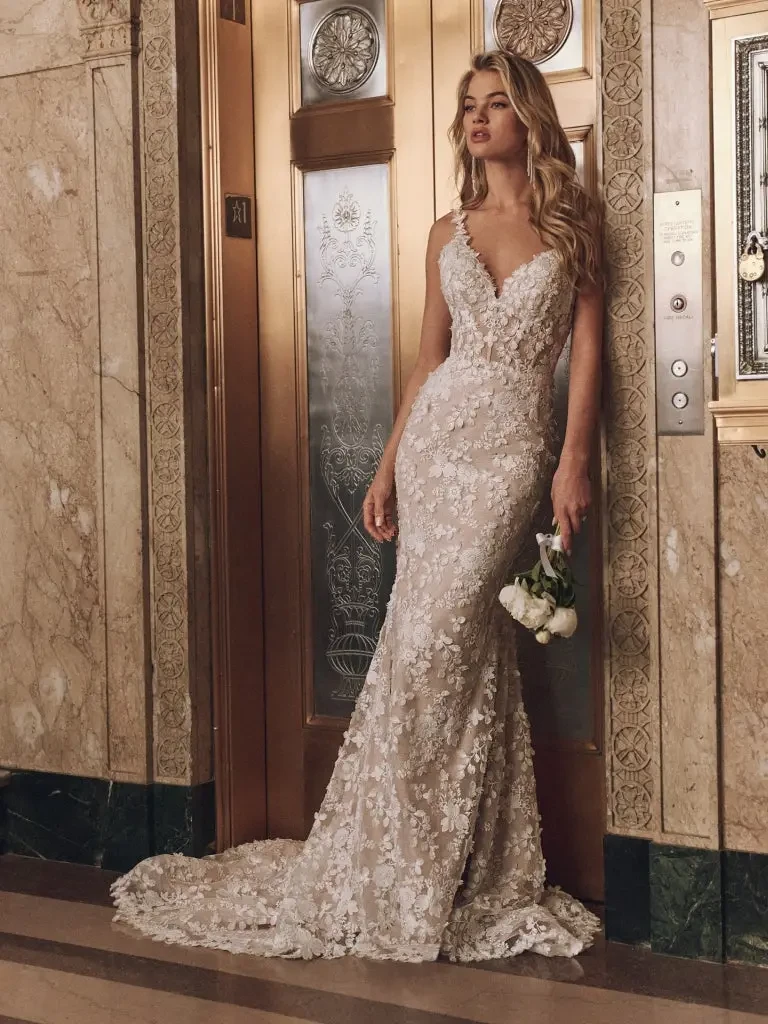 Model is wearing a sleeveless floral lace fit and flare wedding dress