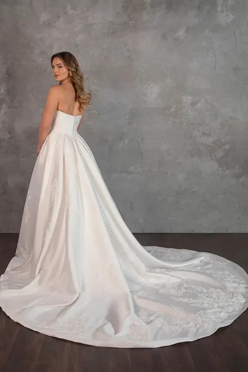 Model is wearing a strapless mikado basque waist ball gown wedding dress by essense of australia