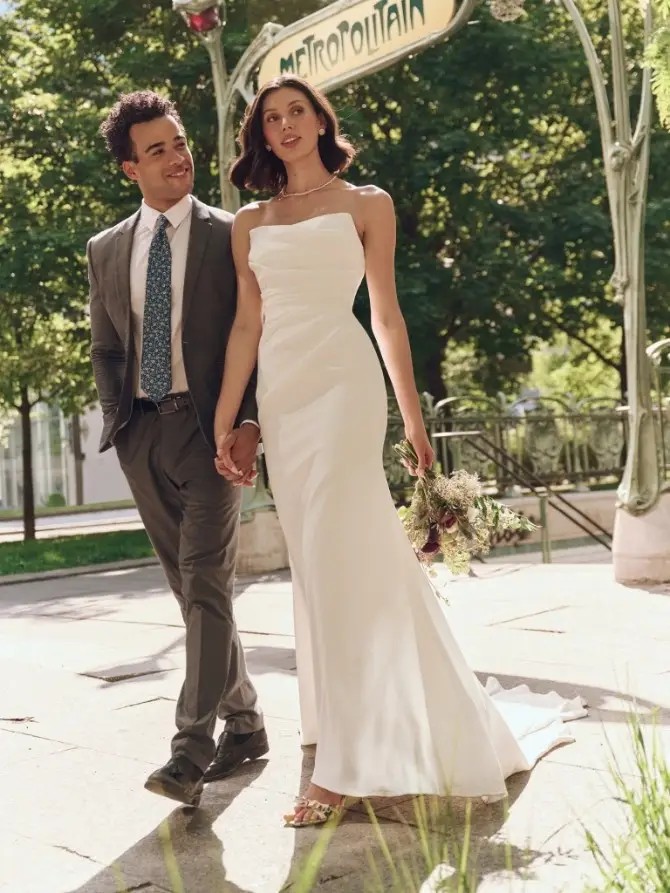 Model is wearing a strapless crepe cat eye neckline bridal gown by rebecca ingram