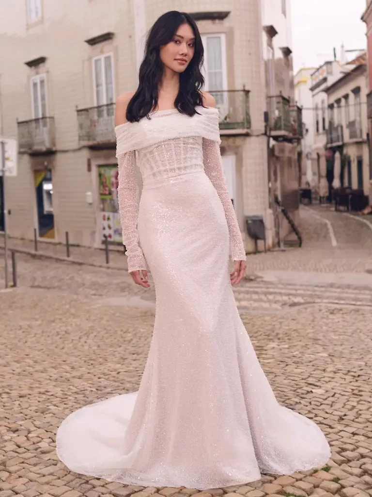 Model is wearing an off the shoulder fit and flare long sleeve wedding dress